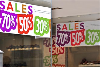 Discount notices showing deductions in shop window of shoe store during the summer sales in shopping street