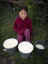 Little Asian girl with freshly milked milk in buckets