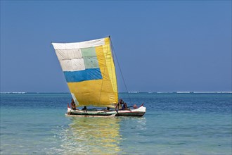 Outrigger boat with colourful sail