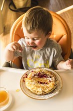 Cute little baby eating pancake plate high chair