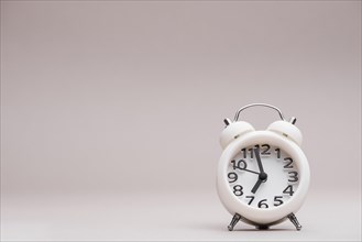 White miniature alarm clock against colored backdrop