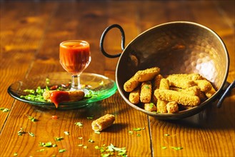 Crispy chicken fingers copper utensil with sauce wooden table