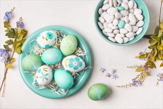 Easter eggs plate near little stones bowl flower twigs