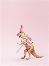 Funny toy dinosaur holding happy birthday sign