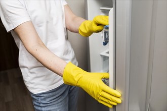 Side view woman cleaning fridge