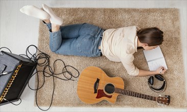 Flat lay female musician home writing song with headphones acoustic guitar