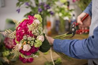 Male florist cutting colorful flower bouquet twigs with pruning shears
