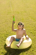 Boy with hat sunglasses playing with water gun