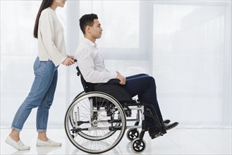 Smiling woman pushing young man sitting wheelchair