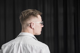 Rear view young man wearing eyeglasses with wireless earphone his ear