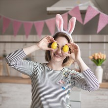 Happy mother with bunny ears holding easter eggs