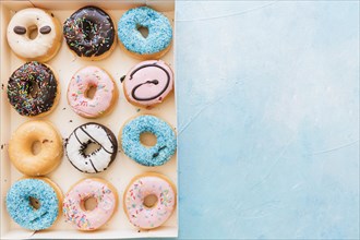 High angle view multi colored fresh donuts box blue background