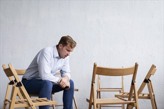 Sad man group therapy session with empty chairs