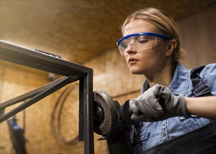 Female welder using angle grinder