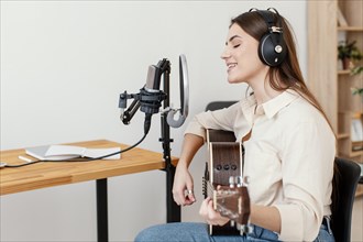 Side view female musician recording song while playing acoustic guitar home