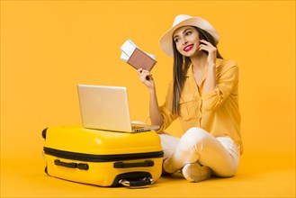 Smiley woman posing luggage while holding plane tickets passport
