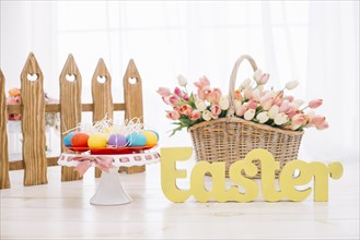 Colorful easter eggs tulips basket with yellow easter text wooden desk