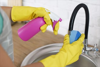 Hand holding spray bottle sponge during cleaning sink home