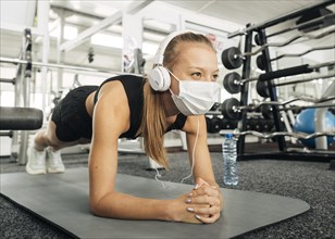 Woman with medical mask headphones working out gym