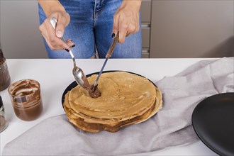 Close up woman spreading peanut butter pancake with spoon knife