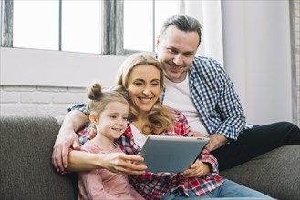 Happy family using digital tablet sofa living room