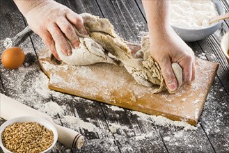 Person kneading dough with flour chopping board
