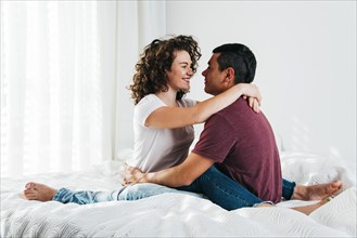 Young man hugging happy woman bed