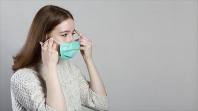 Side view woman putting medical mask with copy space