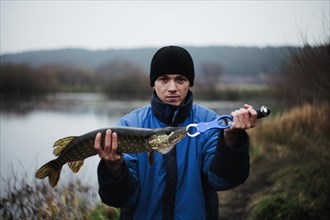 Portrait man holding pike fish