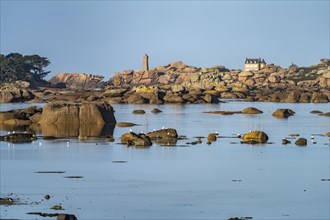 The rocks of the pink granite coast Cote de Granit Rose at the Baie de Sainte Anne near Tregastel with view of the Maison Gustave Eiffel and the lighthouse Phare de Ploumanac'h