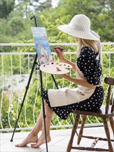 Side view female artist painting outdoors