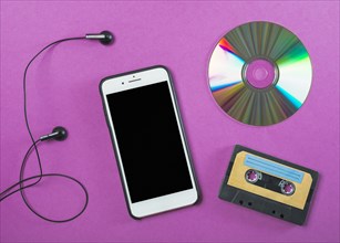 Earphone cellphone compact disc cassette tape purple background