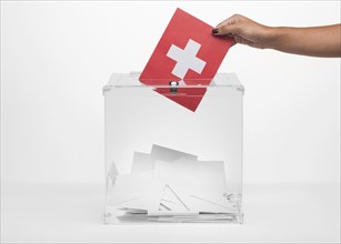 Person putting switzerland flag card into ballot box