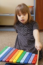 Front view girl with down syndrome playing with xylophone