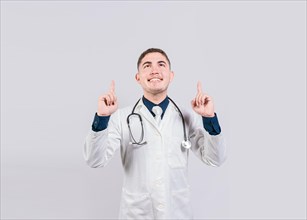 Handsome doctor pointing a advertising up. Happy doctor looking and pointing up isolated. Smiling doctor pointing a promo up