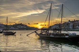 Rabelo boats loaded with port wine barrels on the banks of the Douro at sunset