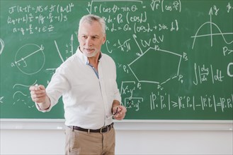 Sociable male teacher standing blackboard pointing by hand