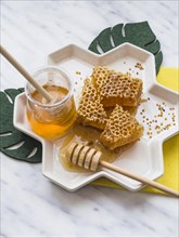 Honey dipper honey comb with bee pollens white tray marble backdrop