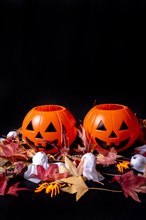 Halloween pumpkins on red autumn leaves and ghosts on a black background