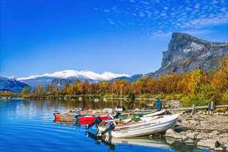 Boats on the lakeshore of a mountain lake with people in autumn at Sarek national park in Sweden
