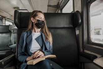 Passenger train wearing medical mask looking out window
