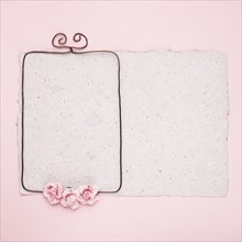 Rectangular wire frame decorated with roses paper against pink background