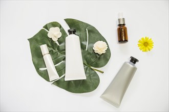 Cosmetic product flower monstera leaf essential oil bottle white background