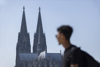Silhouette of passers-by on the Rhine promenade in front of Cologne Cathedral