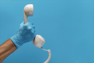Hand with glove holding telephone receiver with copy space