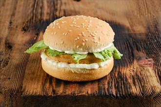 Chicken burger with fresh iceberg lettuce salad on wooden board