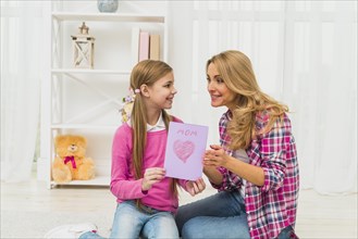 Daughter giving greeting card mother