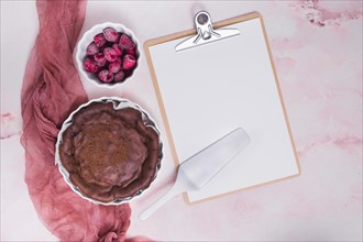 Baked cake raspberry spatula clipboard with white paper pink textured background
