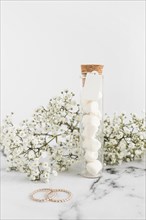 Gypsophila flowers wedding rings marshmallow test tube white background