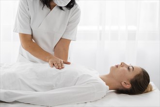 Osteopathist treating female patient by massaging her body